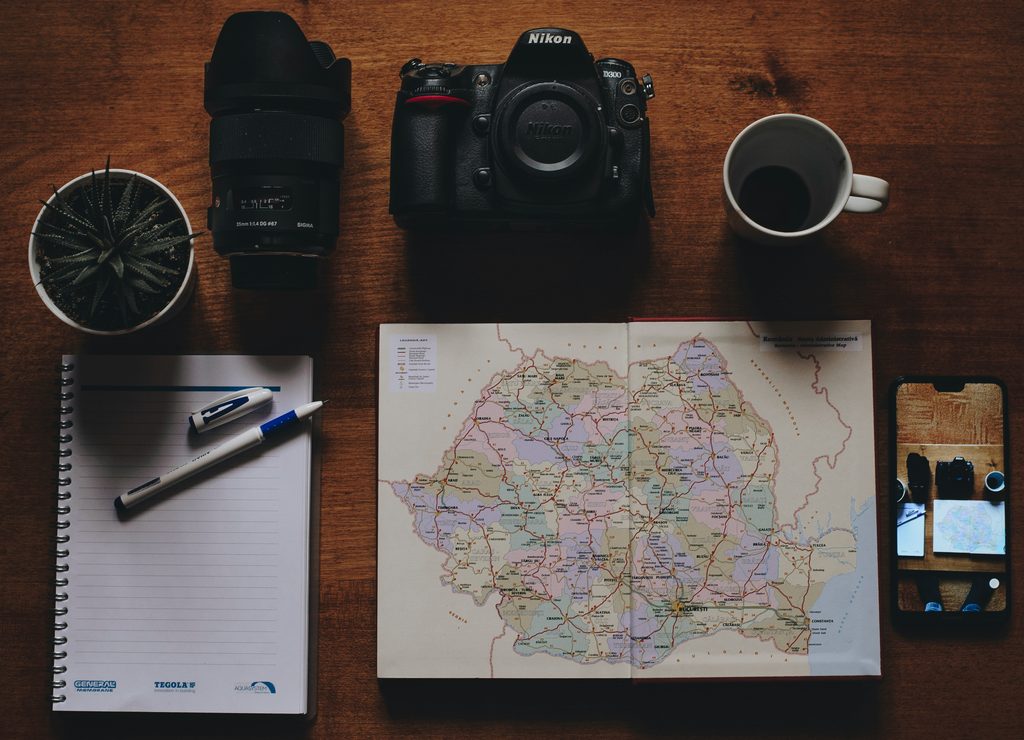 Travel planning workspace with a map, camera, notebook and phone