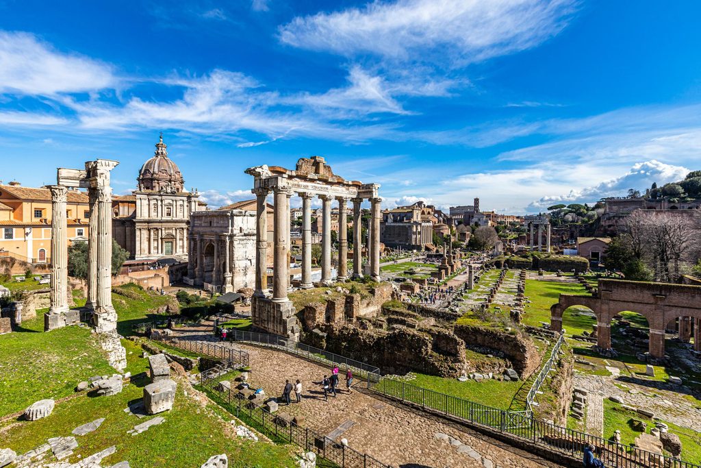Ancient Roman Forum ruins and historic columns in Rome, Italy, under a clear blue sky.
